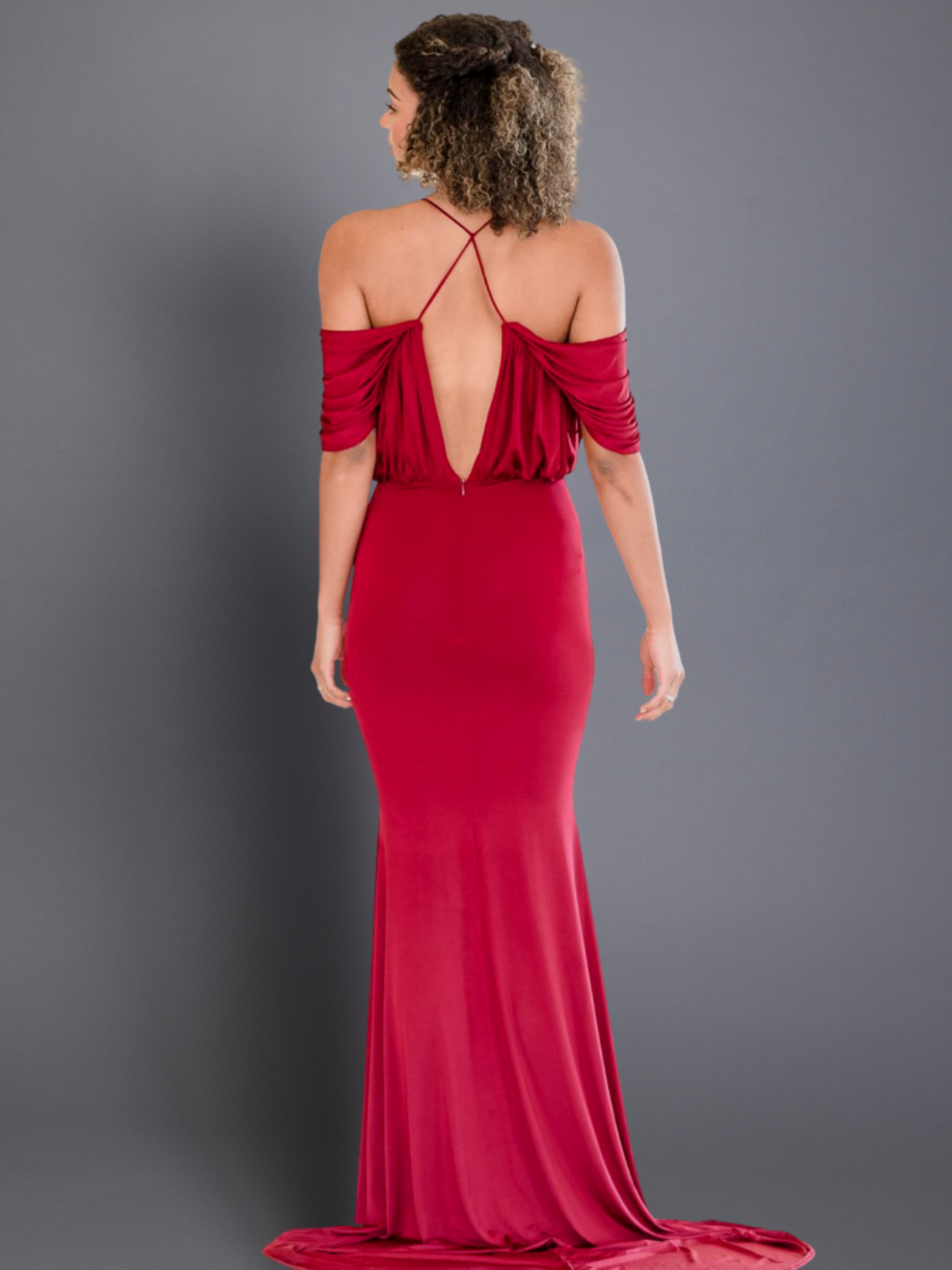 Woman wearing a red evening gown with a plunging neckline on a gray background