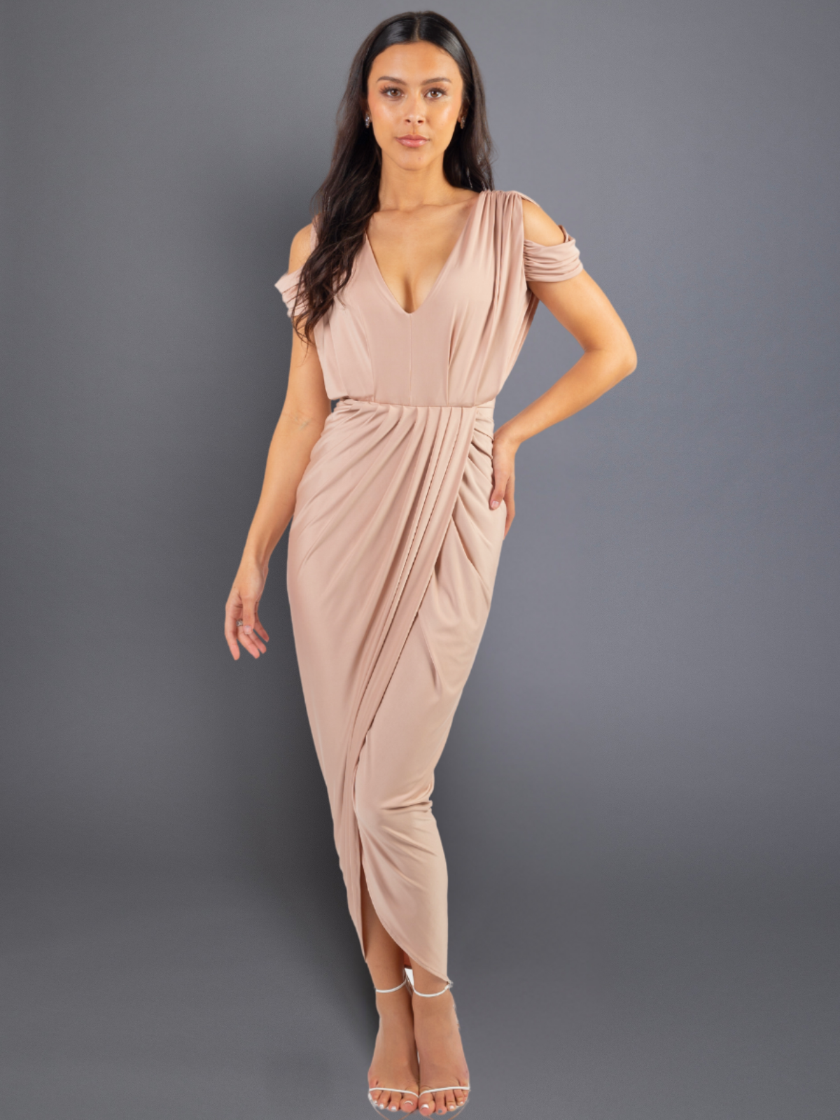 Woman wearing a beige draped dress against a gray background