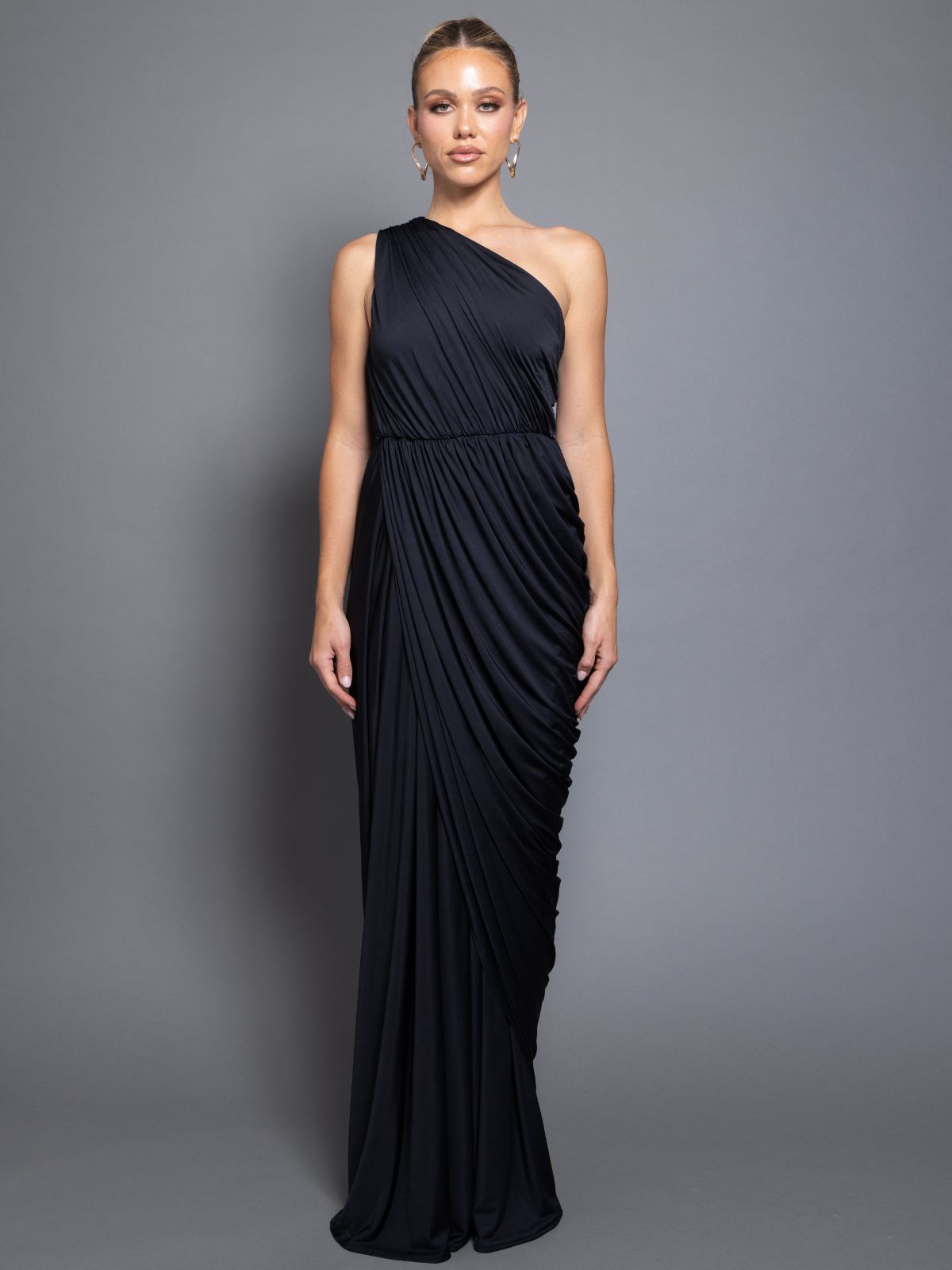 Woman wearing a black one-shoulder gown against a gray background