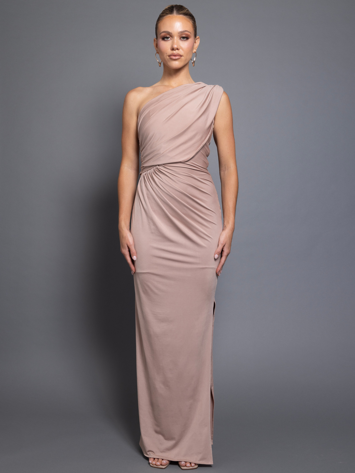 Woman wearing a one-shoulder dress against a gray background